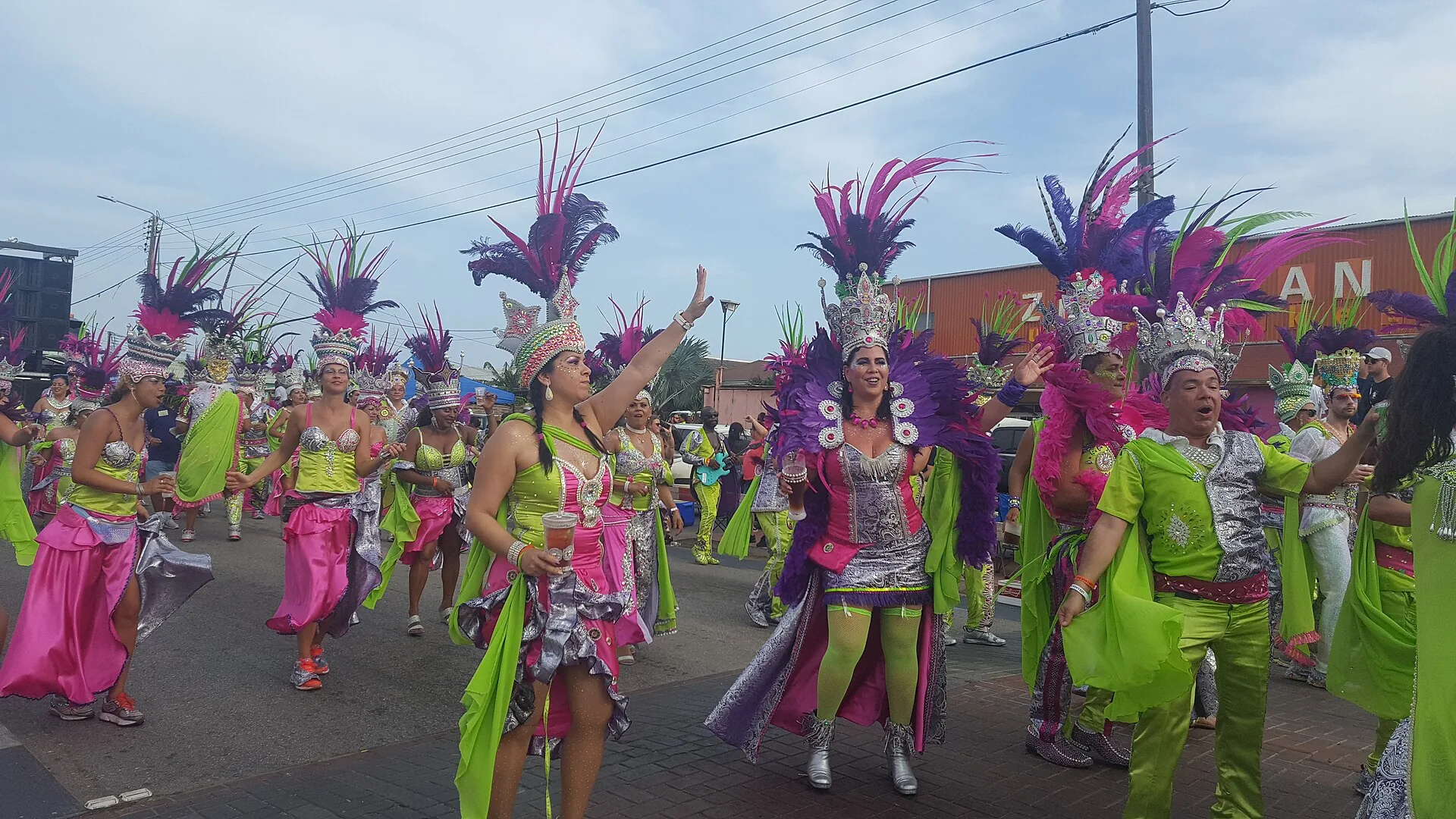 Kleurrijke carnavalgroep op parade in Aruba met uitbundige kostuums van veren en glitter